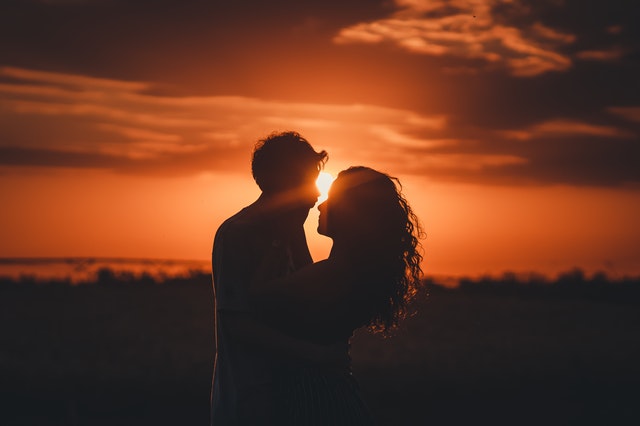 Žena a muž sa bozkávajú v objatí pri západe slnka.jpg